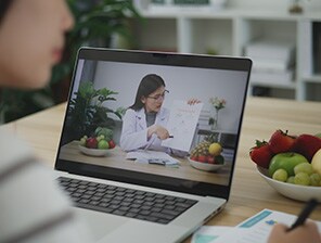 Woman taking notes while consulting with dietitian on her laptop